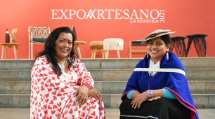 Fotografía de las artesanas Artesanas Adeinis Boscan y Patricia Hurtado sentadas en unas escaleras y con la marca Expoartesano