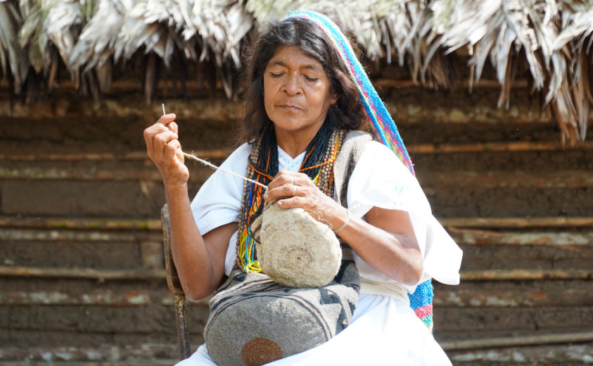 Foto de una artesana del Pueblo Arhuaco tejiendo una mochila