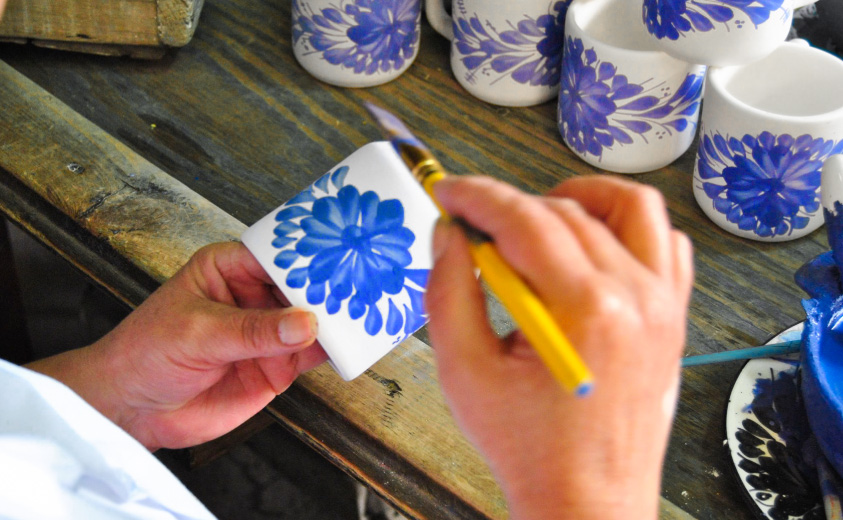 Manos pintando una taza elaborada en cerámica de El Carmen de Viboral