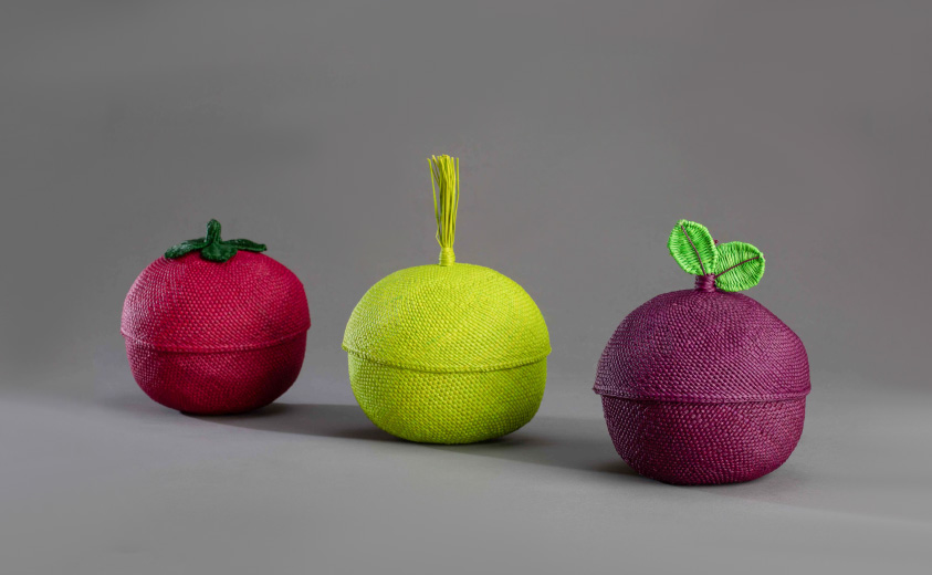Tres frutos tejidos en palma de iraca. Rojo, verde y púrpura. Imagen promocional de la Convocatoria al Carnaval Artesano 2022 en Pasto, Nariño.