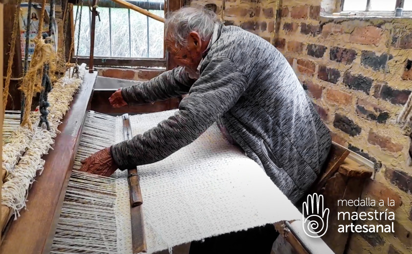 Foto del Maestro artesano Carlos Julio Cristancho acomodando la lana en su telar horizontal