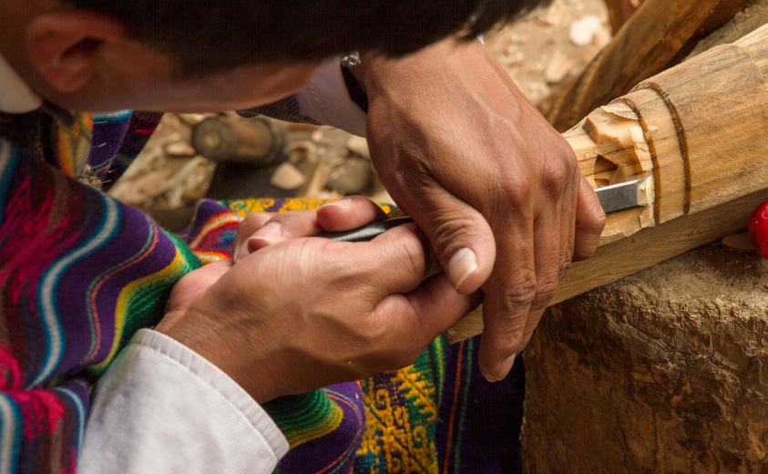 Foto de un artesano tallando una máscara en madera