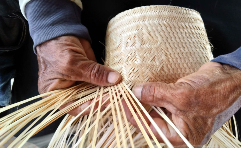 Detalle de manos tejiendo sombrero wayúu